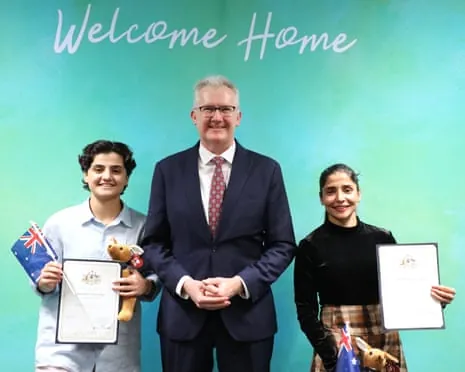 Fatemeh Pasandideh and Atefeh Ramezanisadeh, hold citizenship certificates while standing alongside Australia's minister for home affairs, Tony Burke